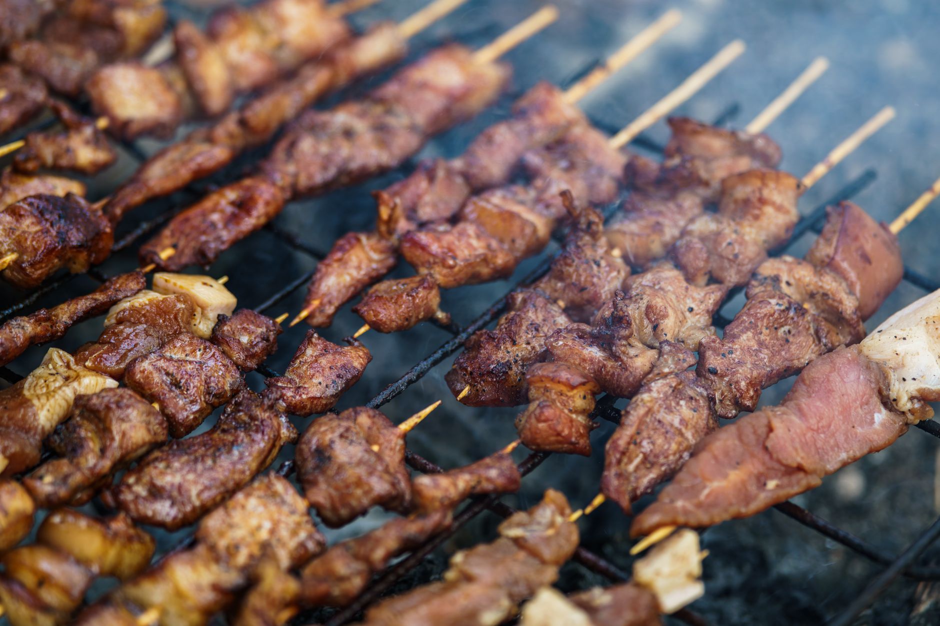 Grilled meat skewers sizzling on an outdoor barbecue grill