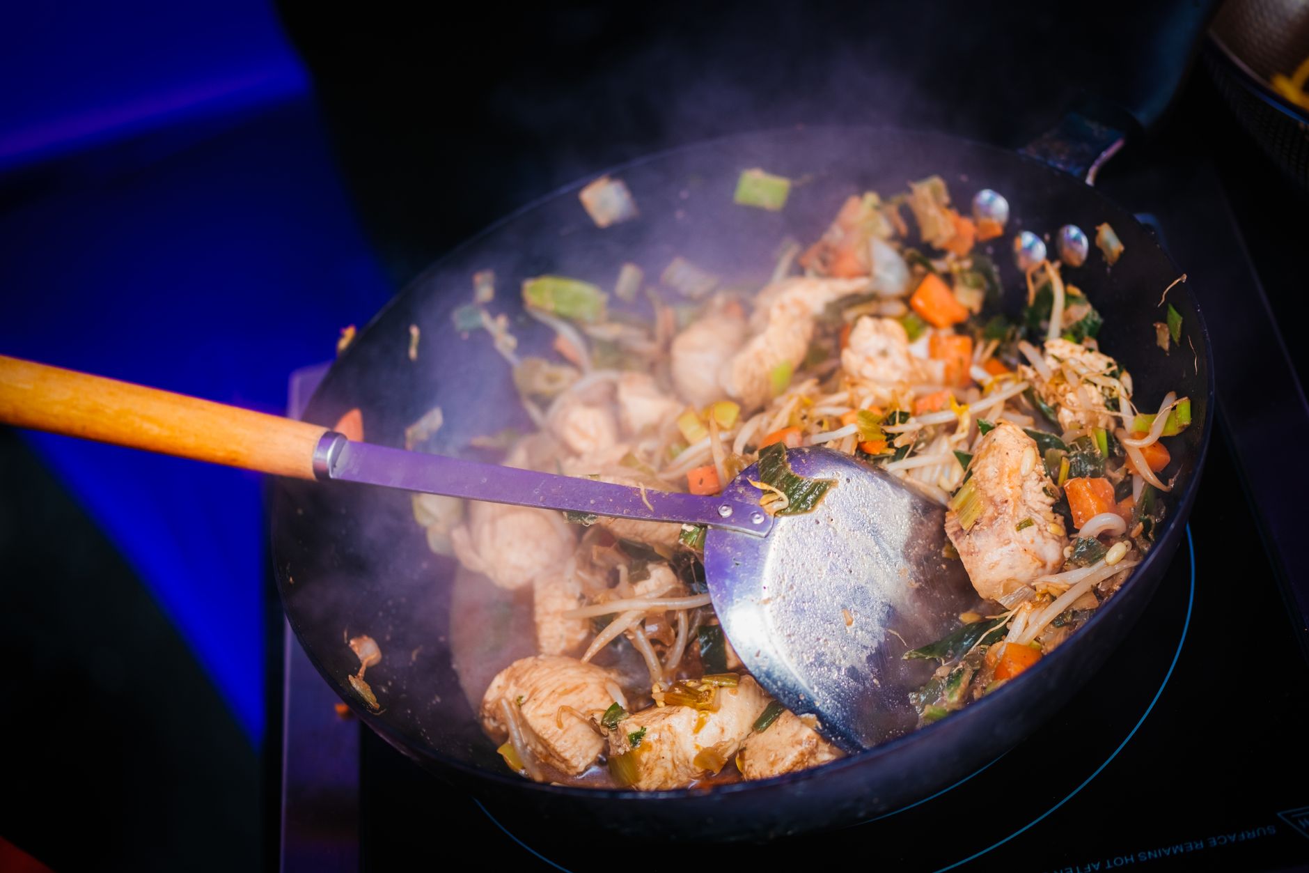 Sizzling chicken stir fry with vegetables cooking in a wok
