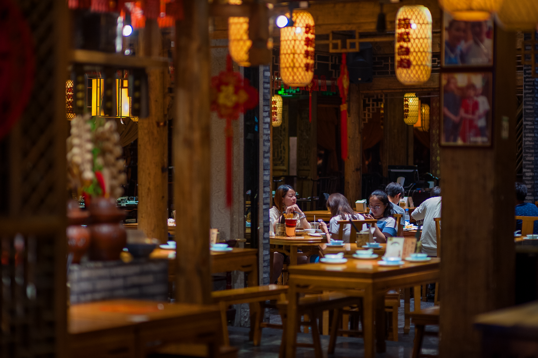 Diners at tables in a warmly lit traditional Asian restaurant interior