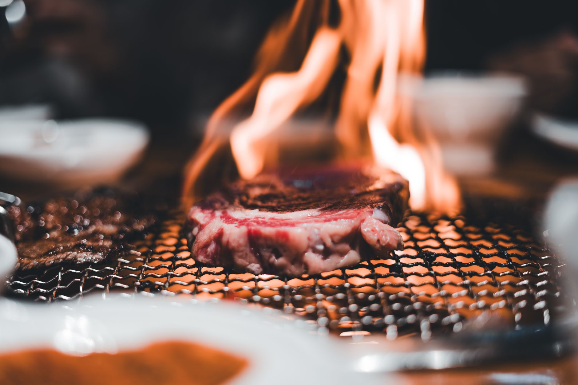 Steak being grilled over an open flame on a hot grill