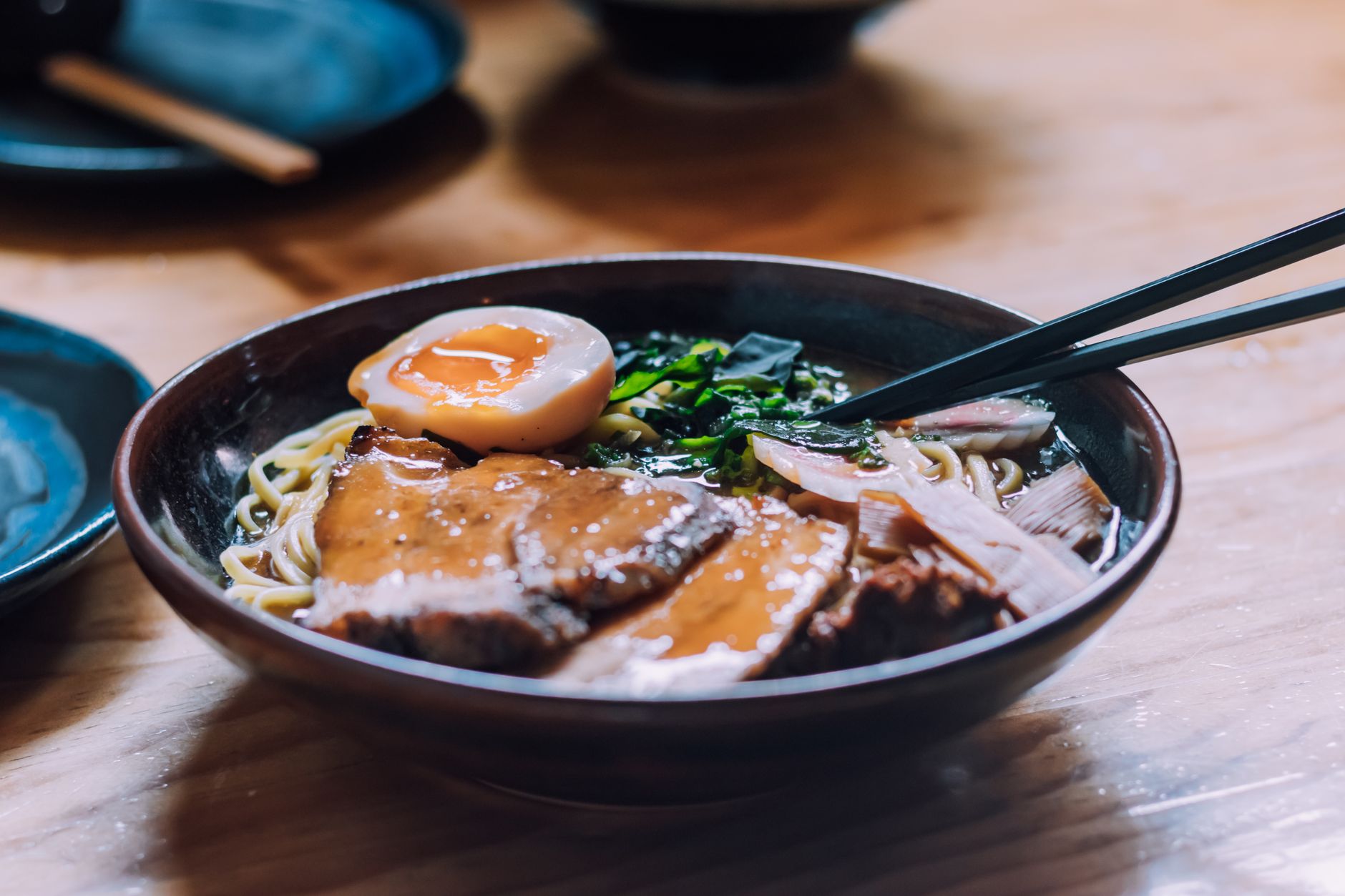 Close-up of a savory ramen bowl with pork, egg, and chopsticks
