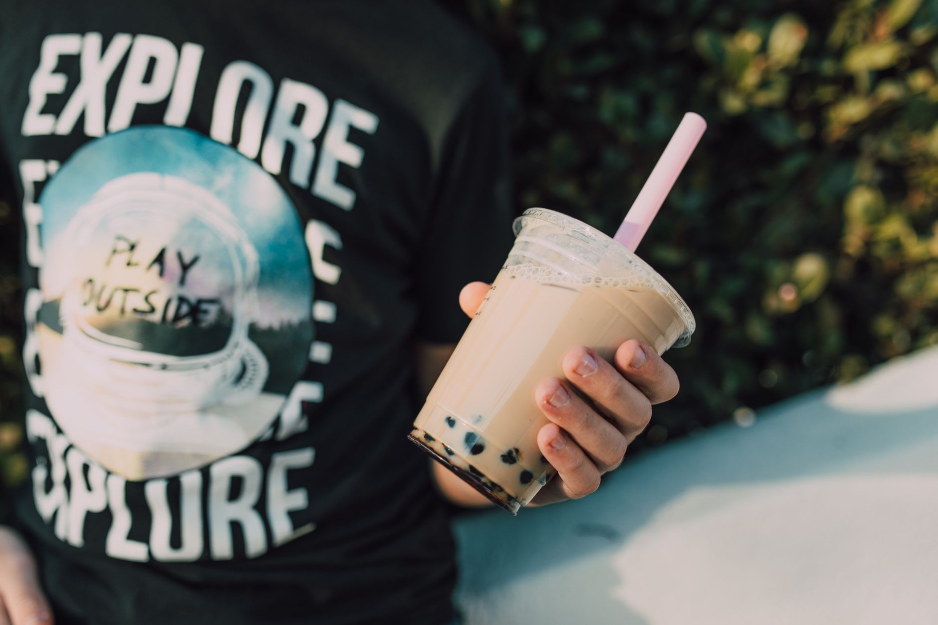 Person holding a bubble tea cup with boba straw outdoors