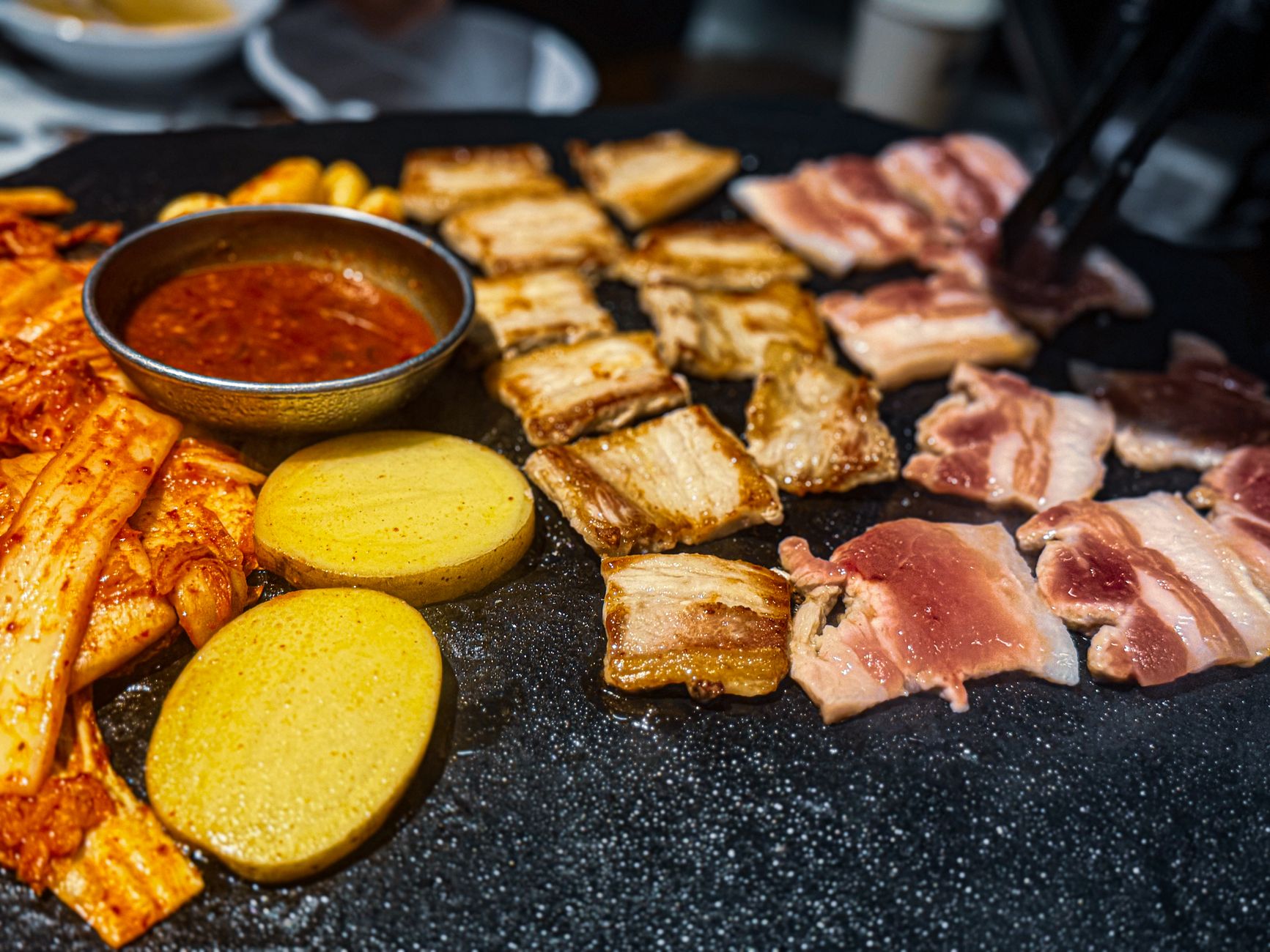 Korean BBQ grill with pork belly, kimchi, and potatoes