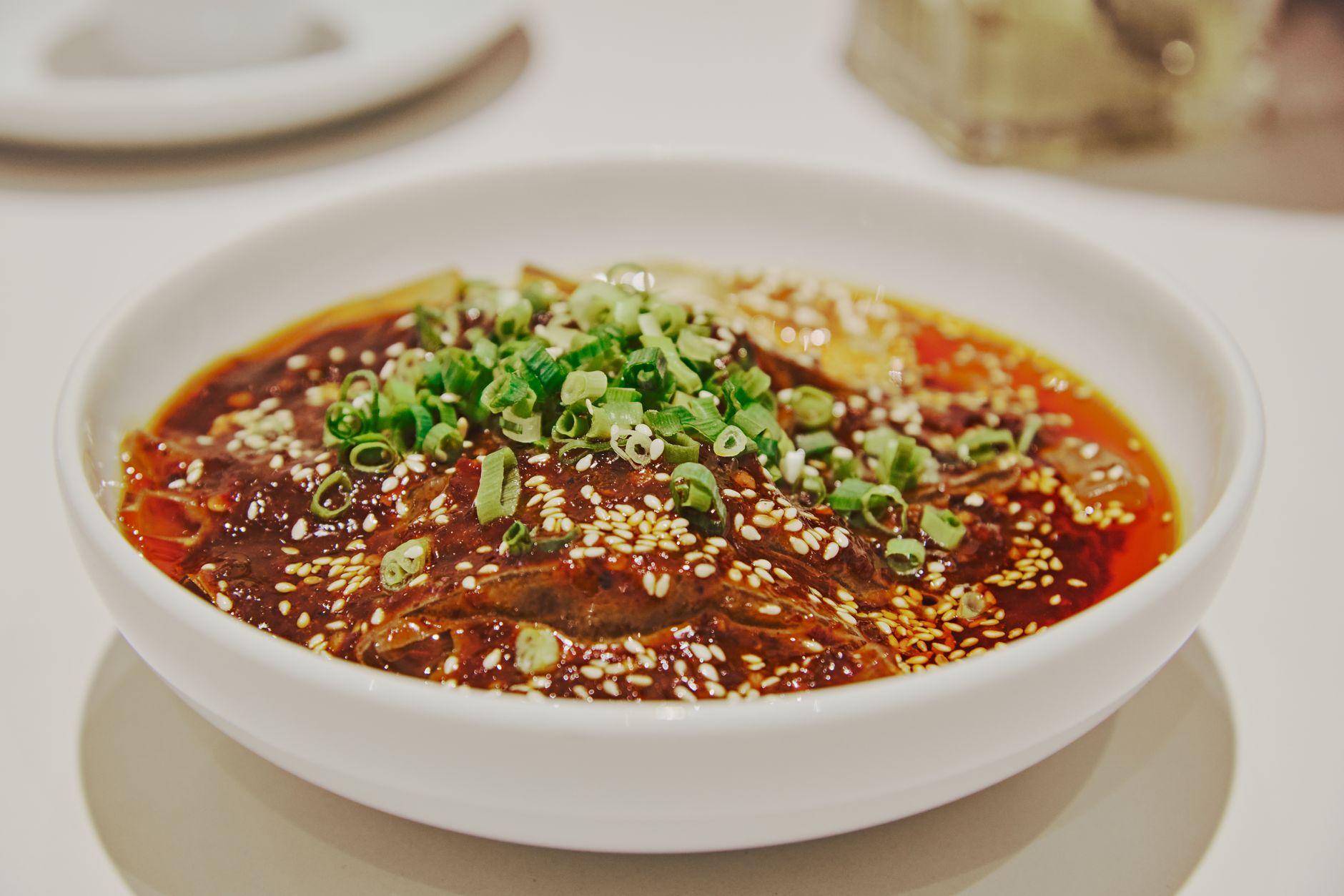 Spicy Sichuan dish garnished with sesame seeds and scallions