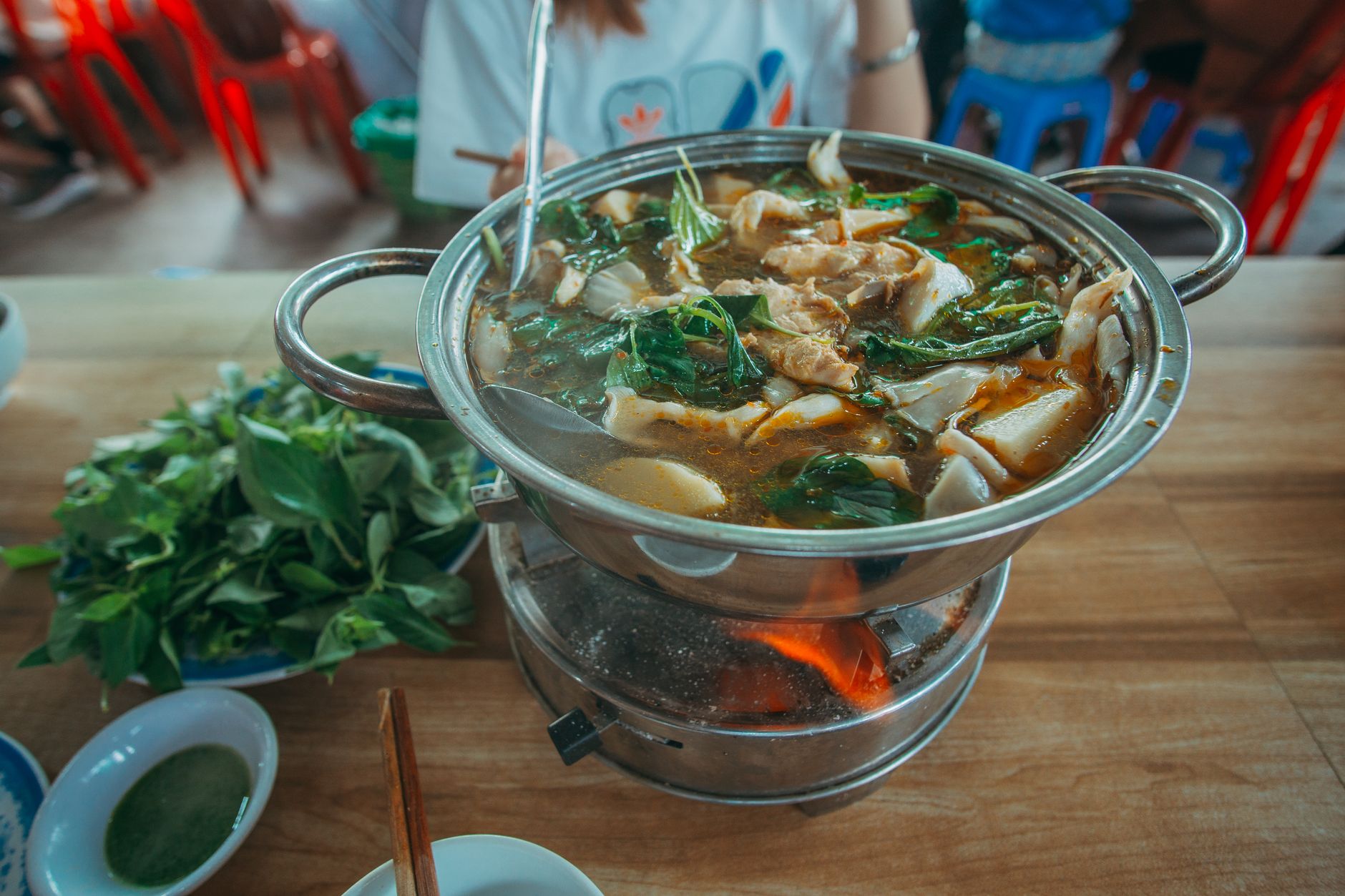 Steaming hot pot with fresh greens and meat on a table