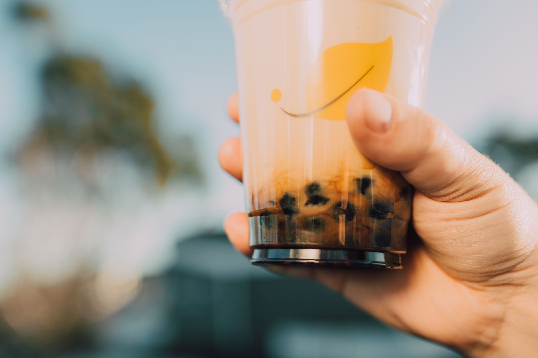 Hand holding a bubble tea cup outdoors