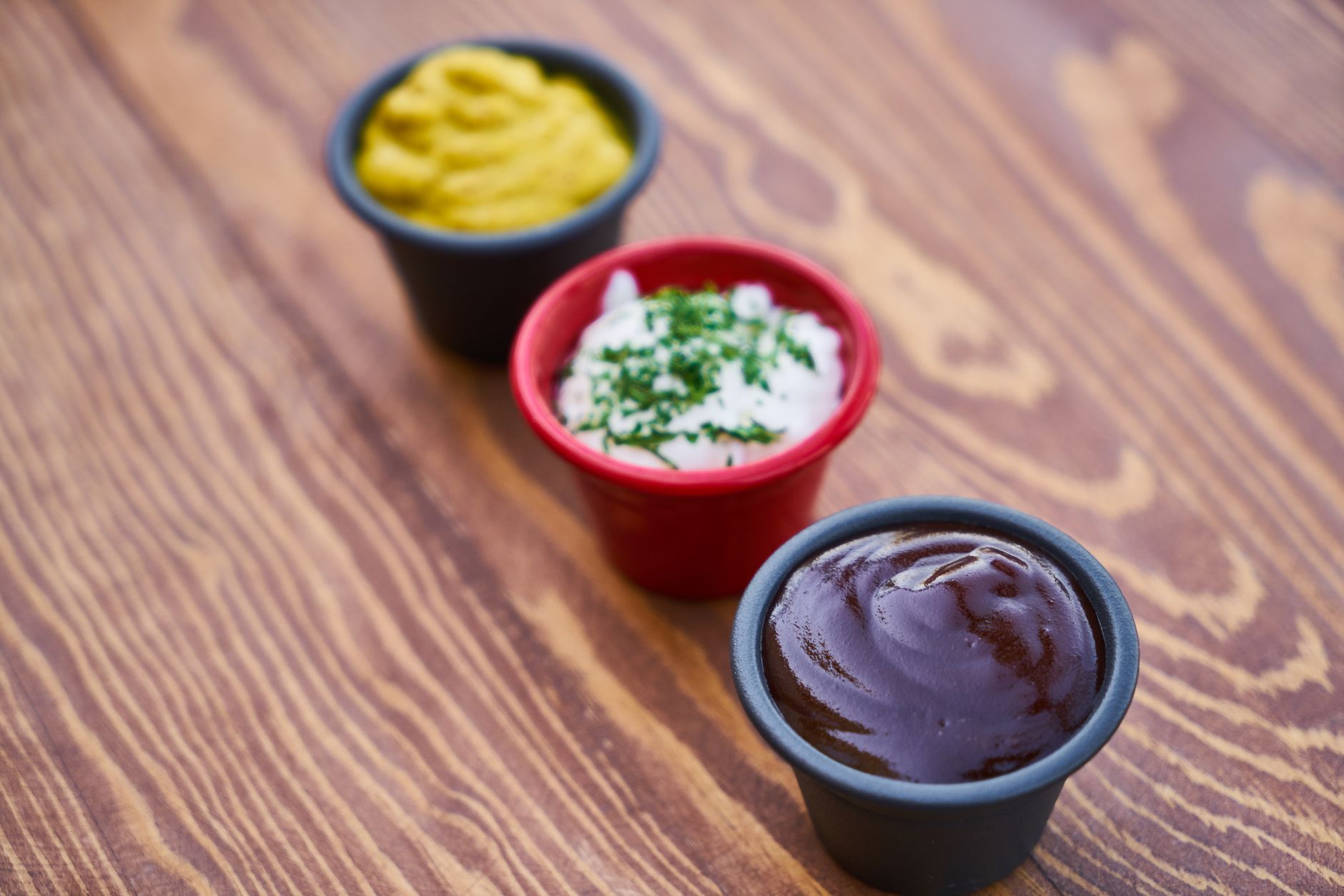 Small dipping sauce cups arranged on a wooden surface