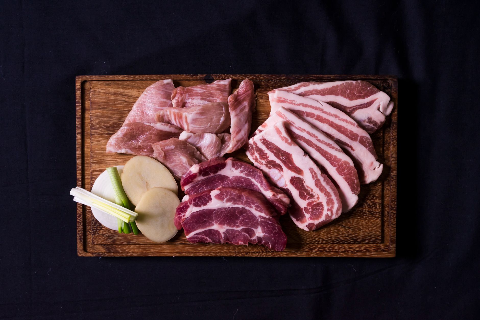 Variety of raw sliced meats arranged on a chopping board for hot pot