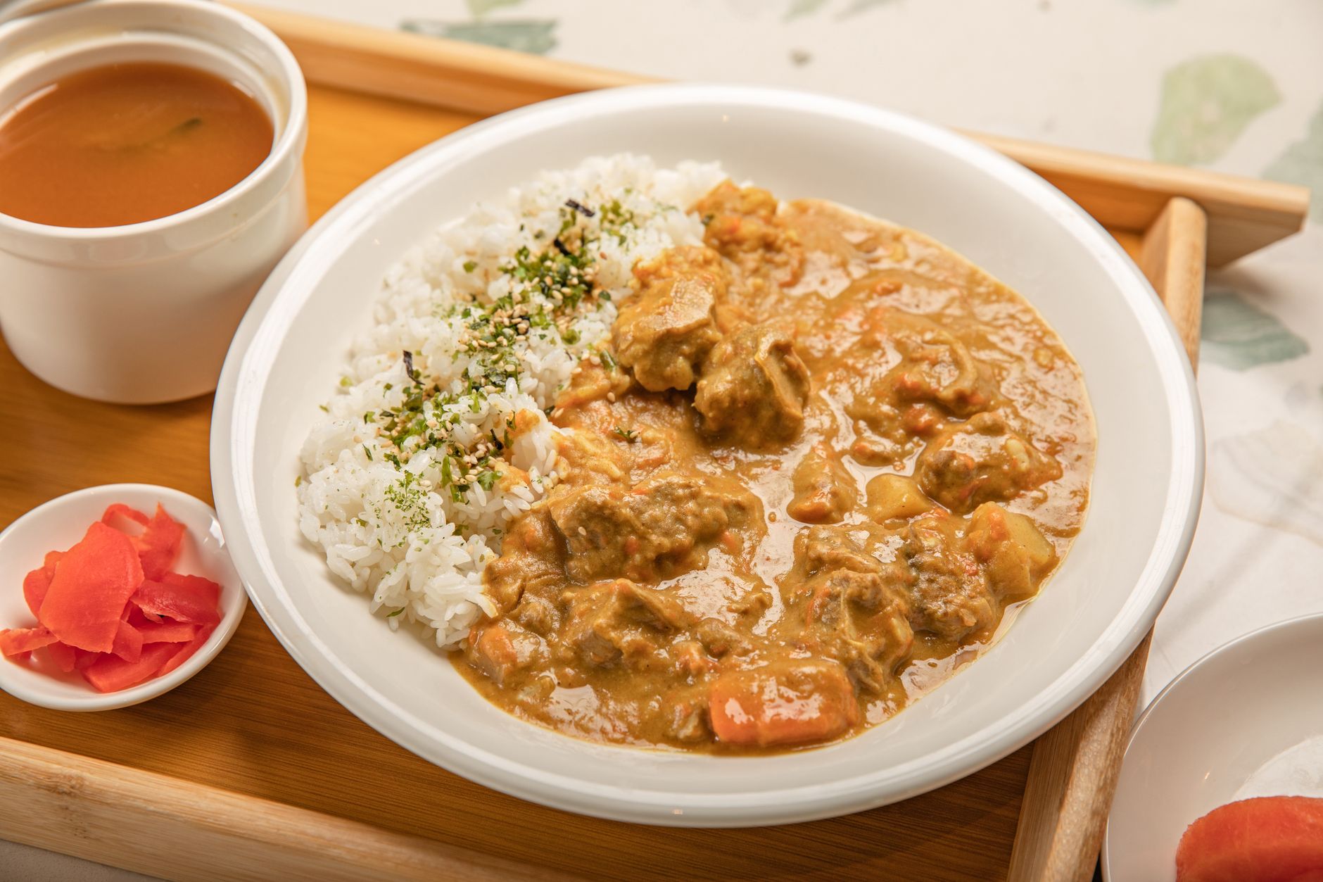 Japanese curry with rice, served with soup and pickles on a wooden tray