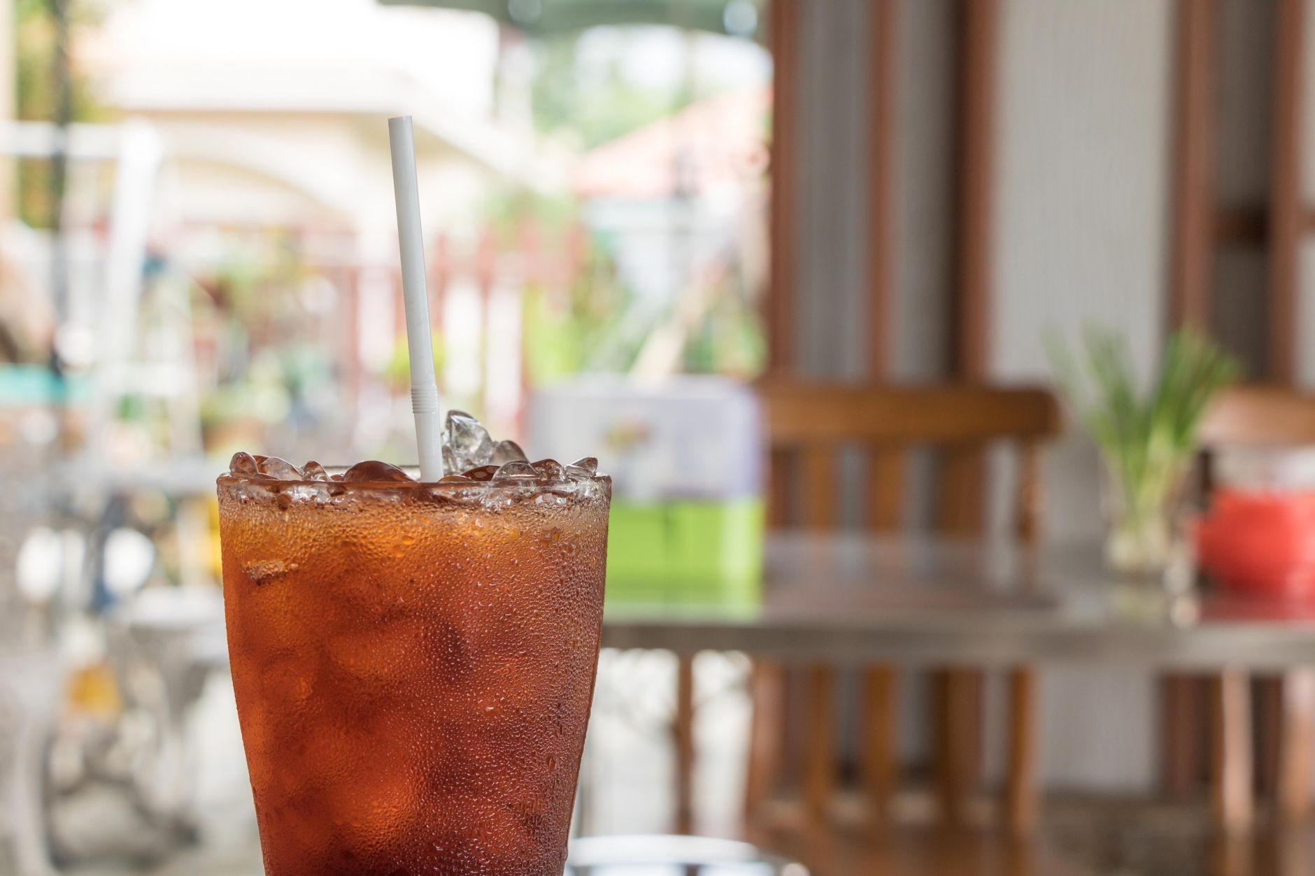 Glass of iced tea with a straw at an outdoor cafe table