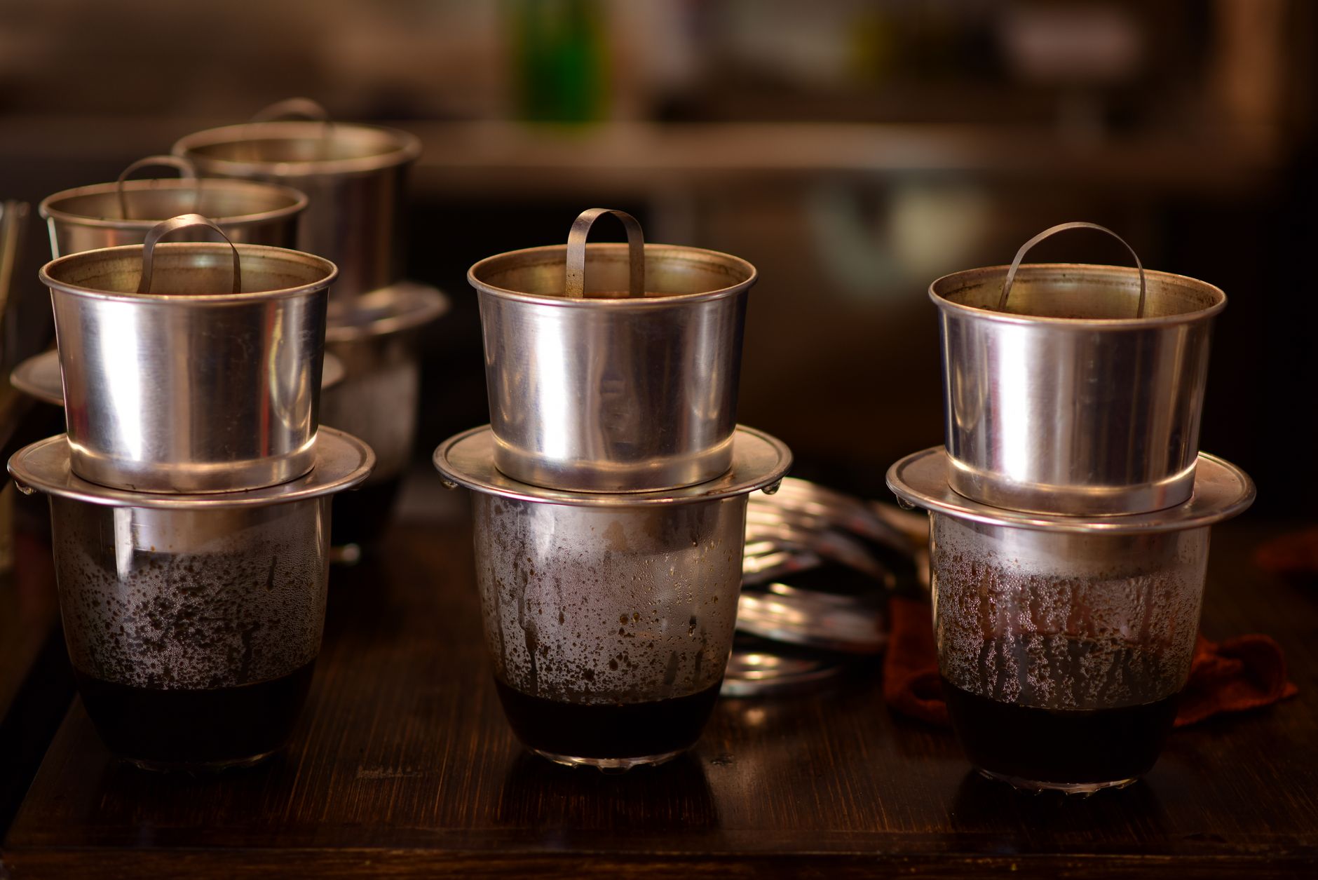 Vietnamese drip coffee phin filters on a dark wooden table