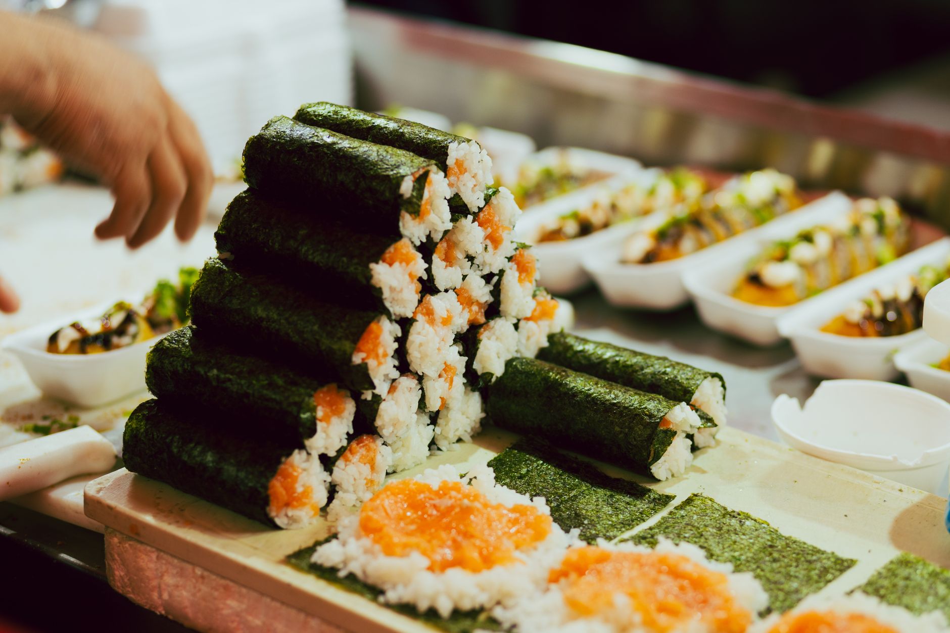 Freshly prepared sushi rolls stacked at a restaurant counter