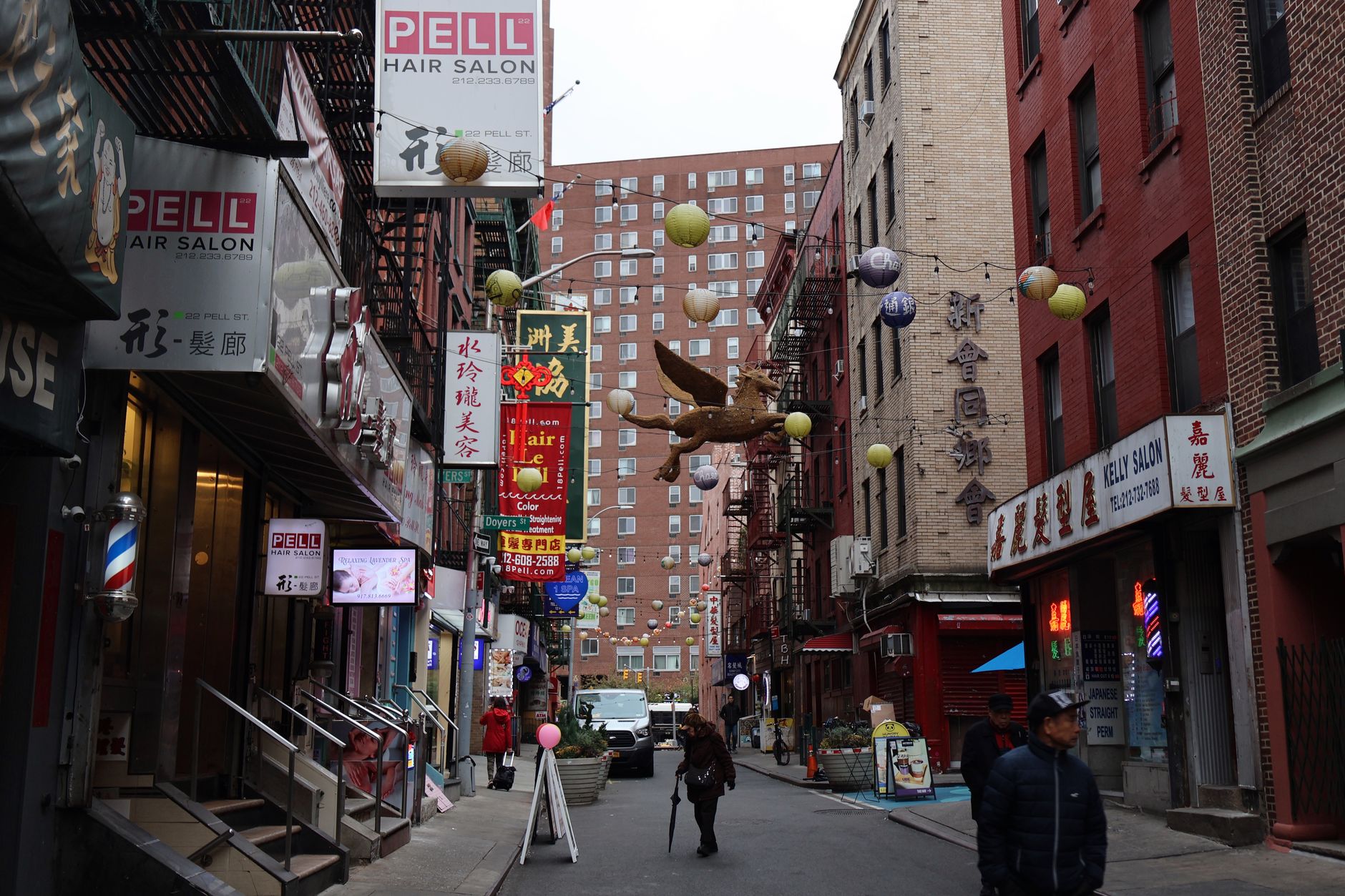 Busy Chinatown-style street in New York City with pedestrians and storefront awnings