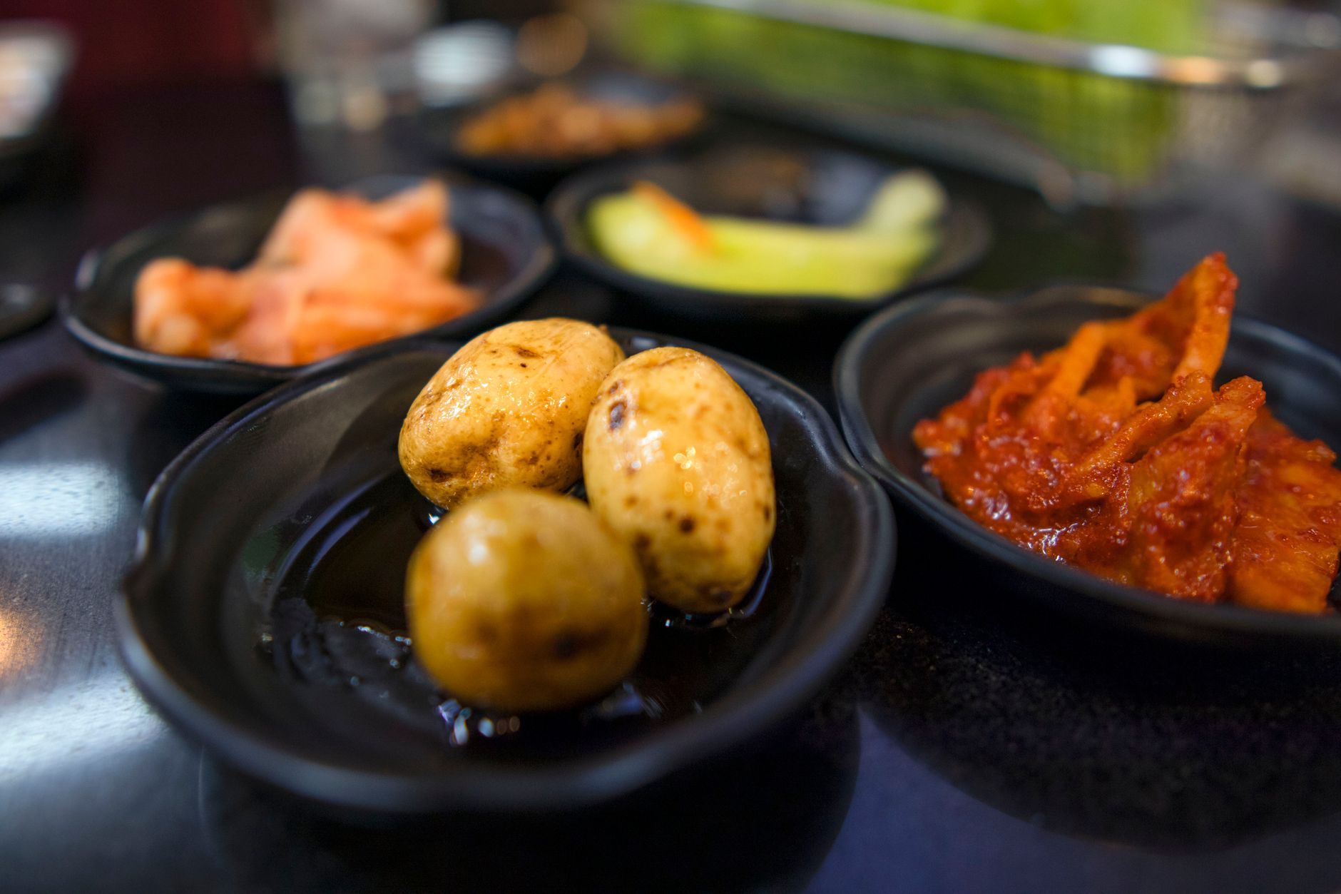 Korean banchan side dishes including kimchi and potatoes on a table