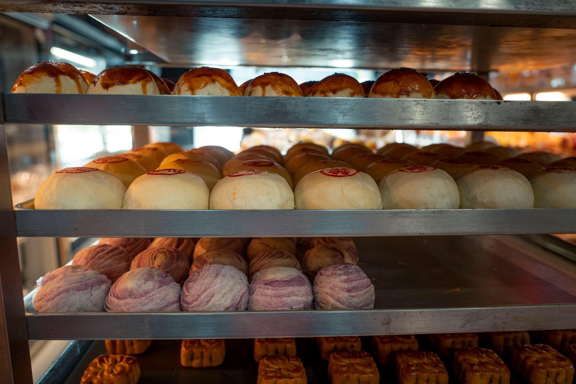 Assorted traditional Asian buns and pastries displayed on bakery shelves