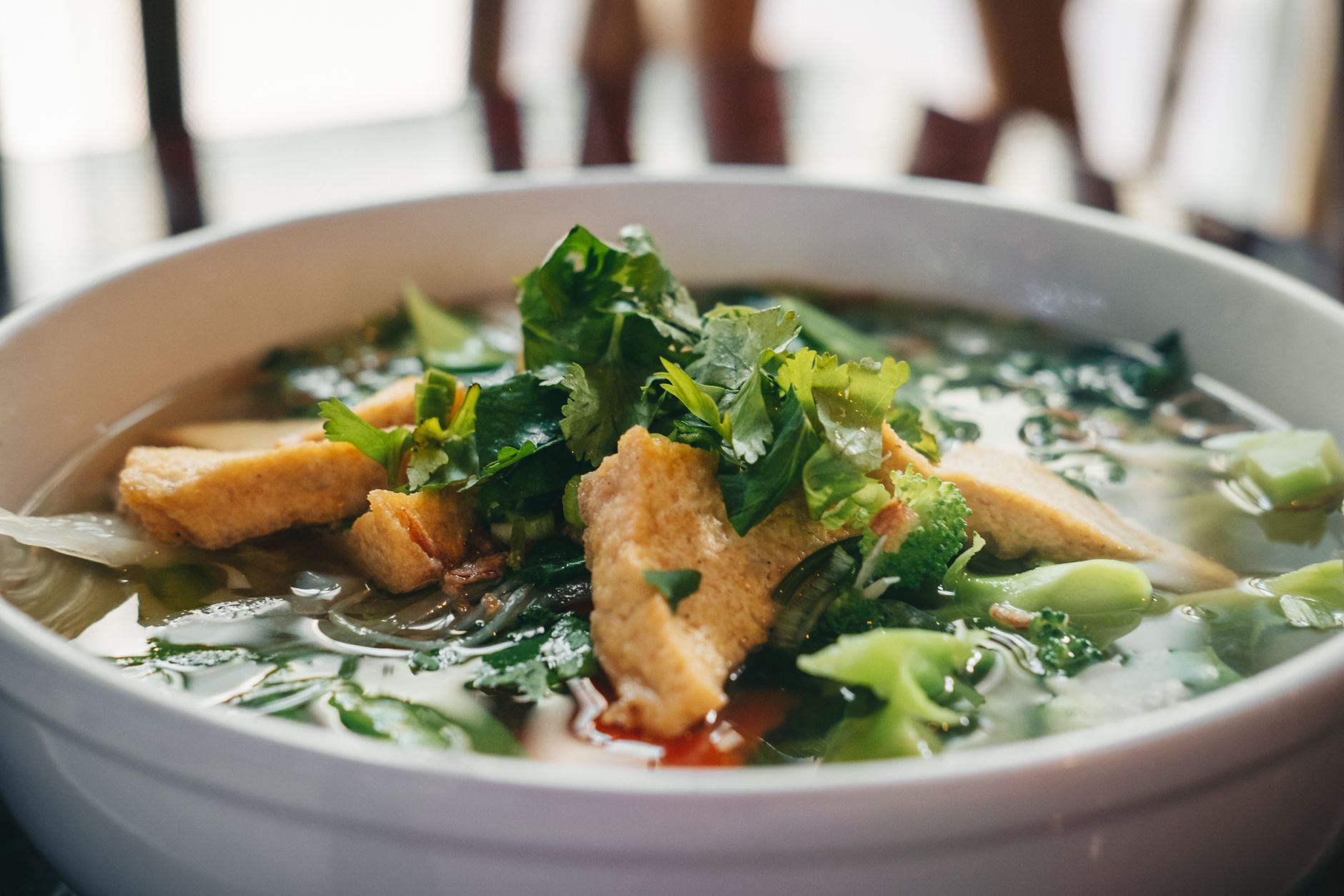 Bowl of Vietnamese pho noodle soup with herbs and greens