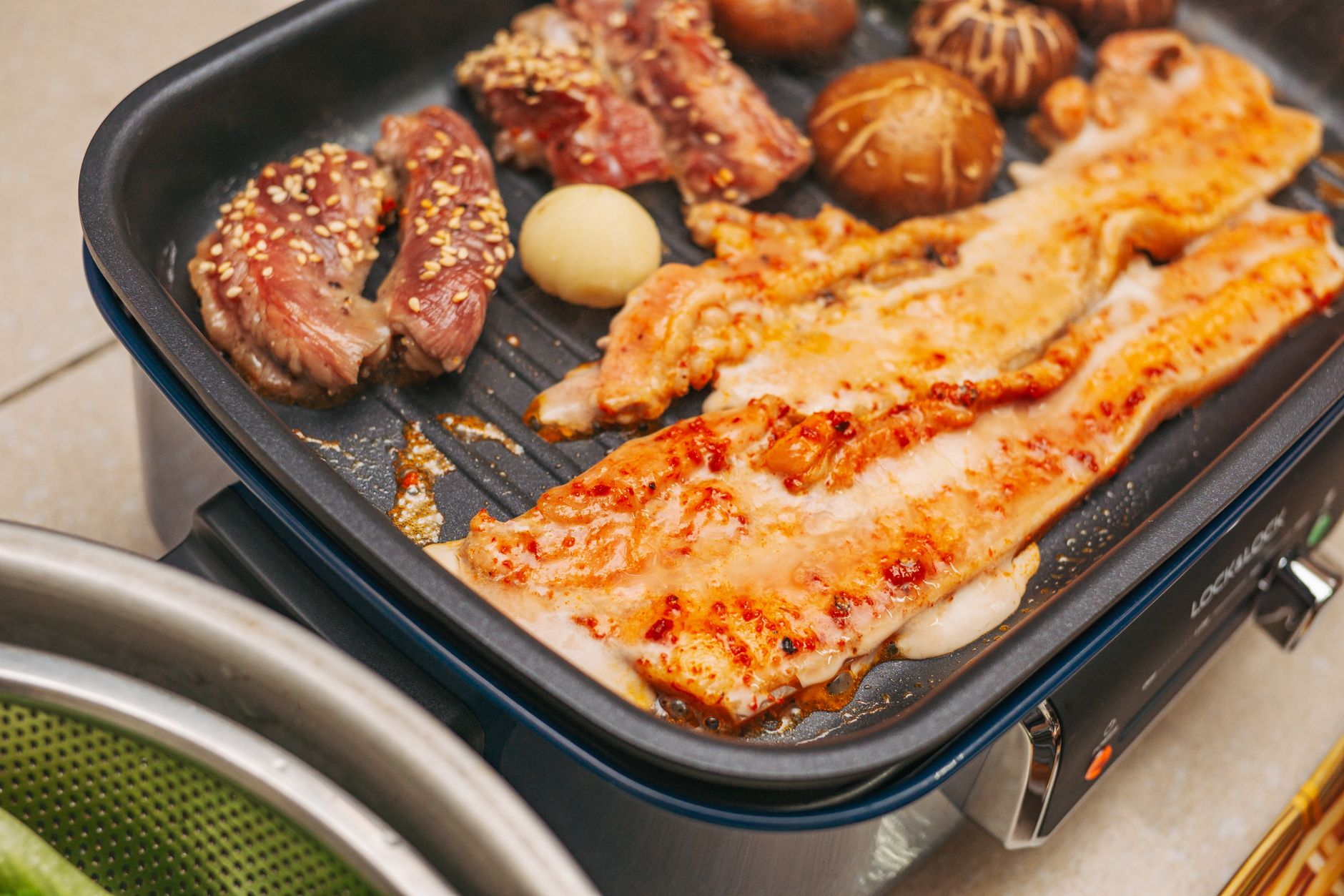 Korean barbecue pork belly, beef, mushrooms and garlic sizzling on a tabletop grill